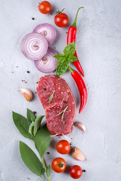 Steak de viande fraîche crue et épices d'assaisonnement sur un fond de béton gris Vue de dessus. Copiez l'espace.