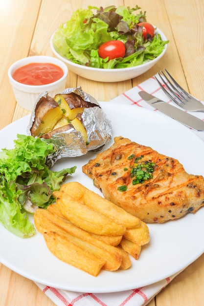 Steak de viande grillé servir avec sauce tomate et salade de légumes sur fond en bois