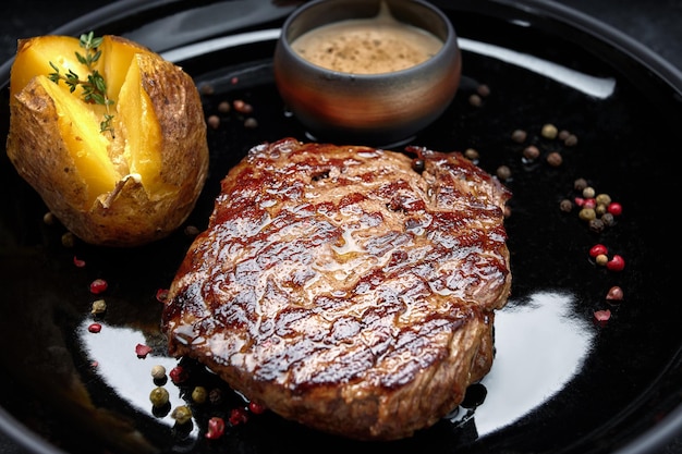 Steak de viande avec pommes de terre au four sur une plaque sombre