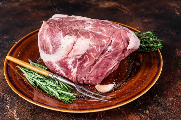 Steak de viande de porc cru frais dans une assiette rustique. Foncé