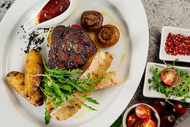 Steak de viande rôti avec pommes de terre frites champignons sauce tomate et herbes