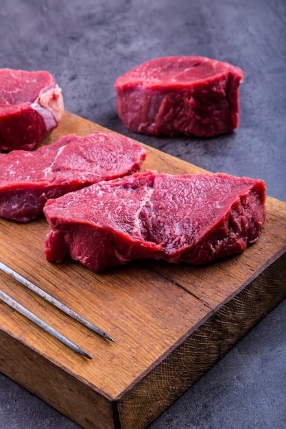 Steaks de boeuf cru sur planche de bois.