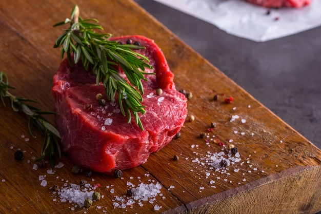 Steaks de boeuf cru avec sel poivre et romarin.