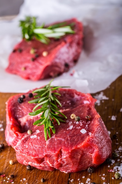 Steaks de boeuf cru avec sel poivre et romarin.