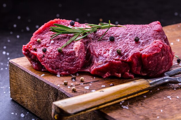 Steaks de boeuf cru avec sel poivre et romarin.