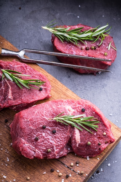 Steaks de boeuf cru avec sel poivre et romarin.