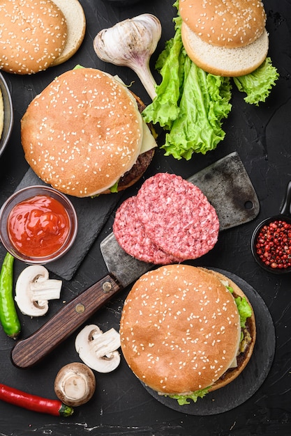 Steaks de boeuf haché et deux hamburgers sur fond noir, mise à plat