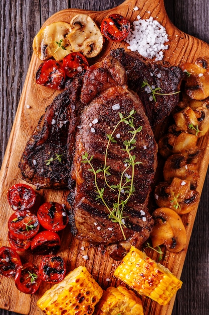 Steaks de boeuf avec tomates grillées, champignons et maïs.