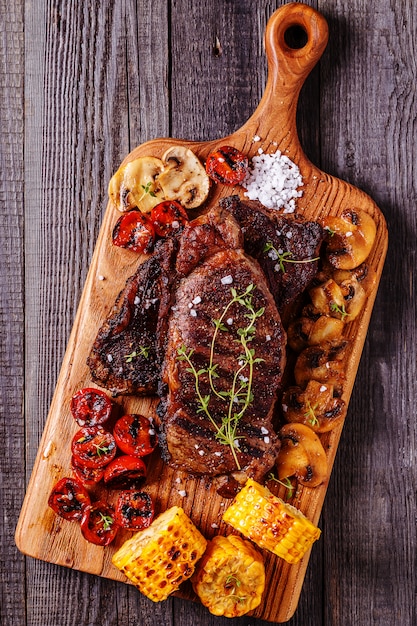 Steaks de boeuf avec tomates grillées, champignons et maïs.