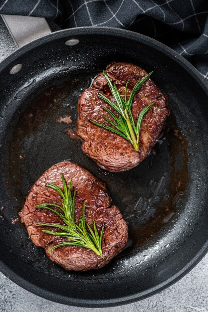 Steaks de boeuf de viande de filet mignon de filet mignon grillés dans la casserole. Fond blanc. Vue de dessus.