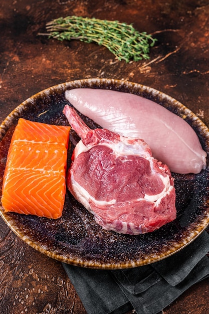 Steaks crus non cuits - poisson saumon, boeuf ou veau et filet de poitrine de dinde. Fond sombre. Vue de dessus.