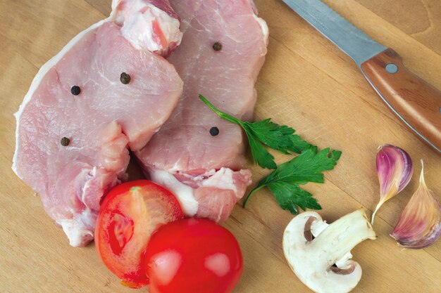 Steaks crus non transformés avec champignon de poivre d'épice de tomate à l'ail et couteau sur une surface en bois