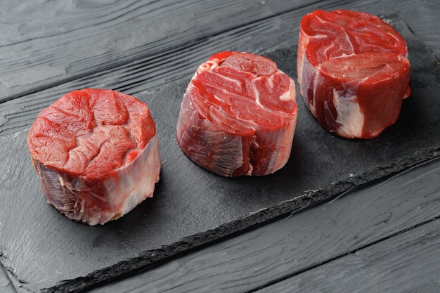 Steaks de filet de boeuf cru sur table en bois noir