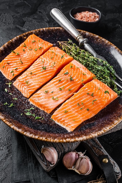 Steaks de filet de saumon poisson cru au thym et aux herbes Fond noir Vue de dessus