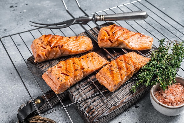 Photo steaks de filets de saumon grillés avec sel, poivre et herbes sur le gril fond gris vue de dessus