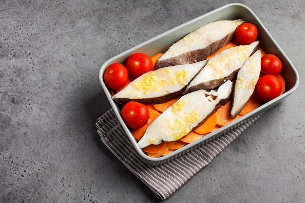 Steaks de flétan réfrigérés dans un plat allant au four avec tomates et patates douces copie espace plat de poisson