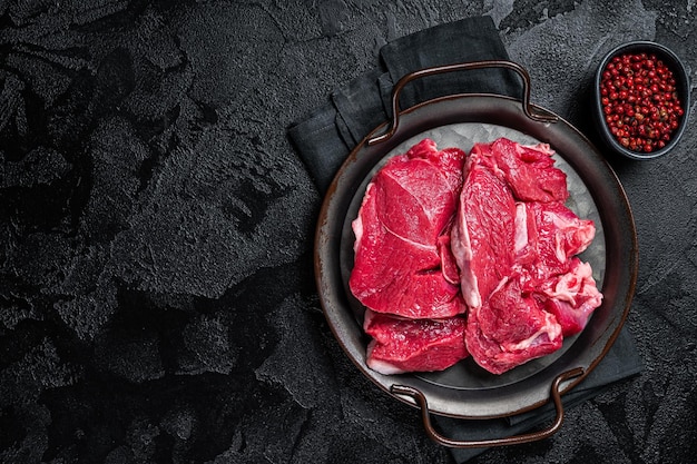 Steaks de jambe d'agneau crus sur la table de boucher Fond noir Vue de dessus Espace de copie