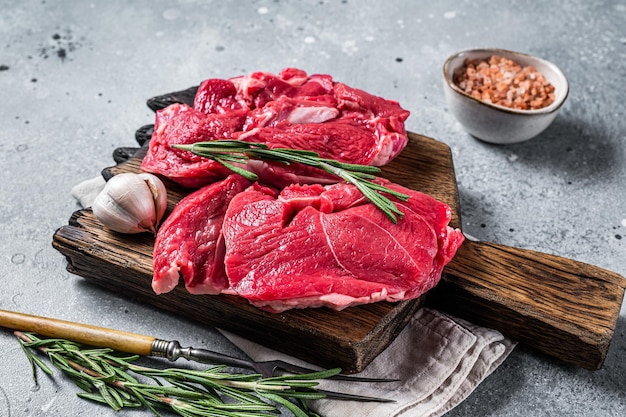 Steaks de jambe de côtelette d'agneau cru non cuits sur une planche à découper Fond gris Vue de dessus