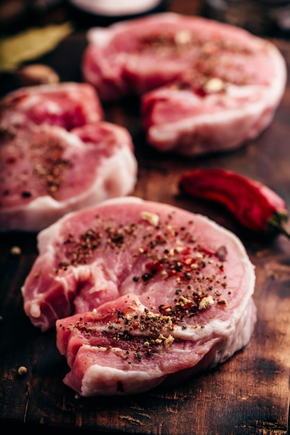 Steaks de longe de porc aux épices moulues sur une planche à découper rustique