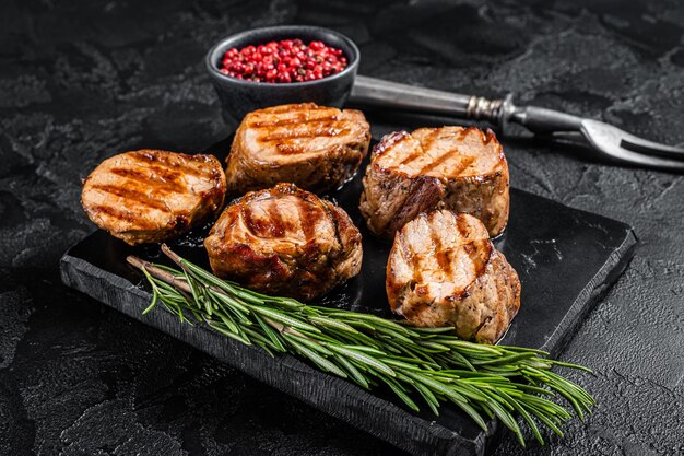 Steaks de médaillons de porc grillés au BBQ, viande de filet mignon. Fond noir. Vue de dessus.