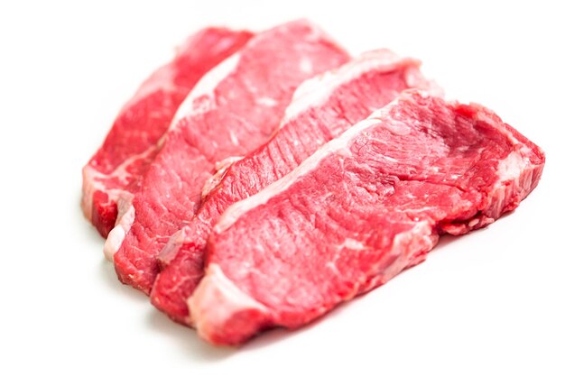 Steaks de New York crus sur fond blanc.