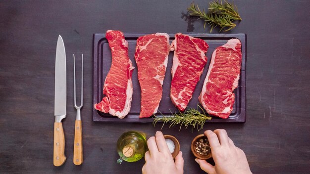 Steaks de New York crus sur une planche à découper en bois.