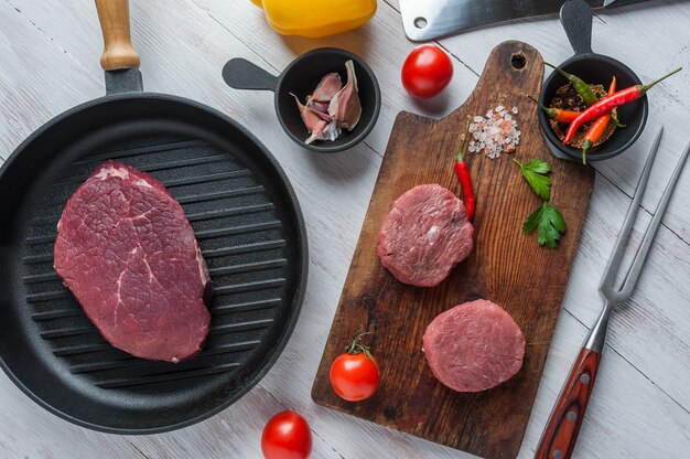 Steaks sur planche à découper, prêts à cuire. Viande crue fraîche, surface en bois, pose à plat