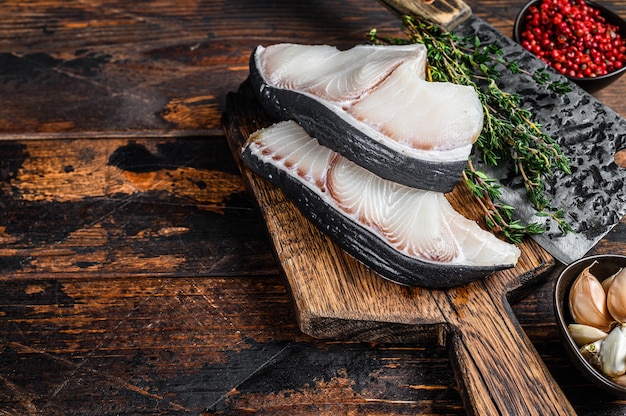 Steaks de poisson cru de requin bleu sur une planche à découper avec couperet.