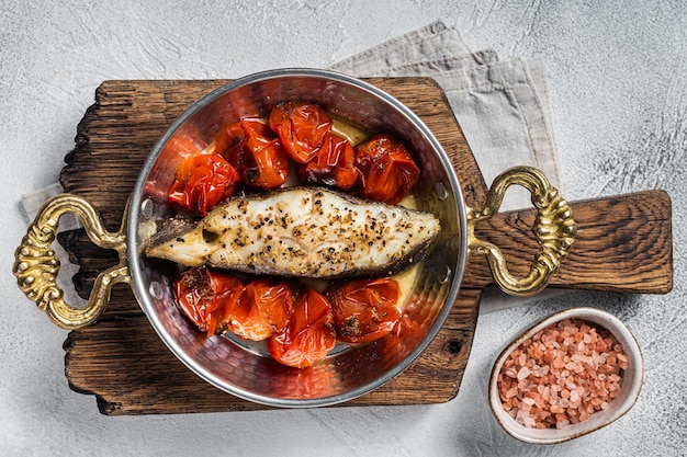 Steaks de poisson flétan frit avec tomate dans une poêle Fond blanc Vue de dessus