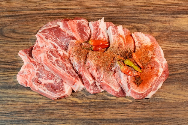 Steaks de porc marinés sur planche à découper et ingrédients pour la cuisine