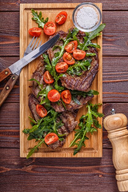 Steaks à la roquette et tomates sur planche de bois