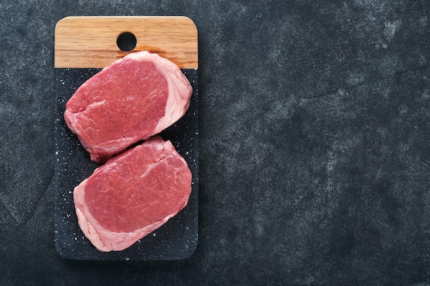 Steaks Steaks de filet mignon frais aux épices romarin et poivre sur planche de marbre noir sur fond gris Vue de dessus