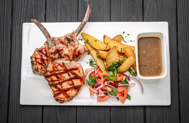 Steaks Tomahawk fraîchement grillés, avec pommes de terre frites, légumes et sauce