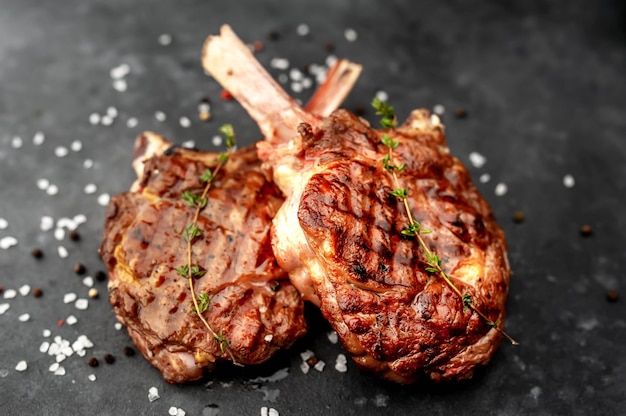 steaks - tomahawks de boeuf grillés aux épices, thym sur fond de pierre.