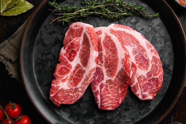 Steaks de viande de cou de porc frais sur une vieille table en bois sombre fond vue de dessus mise à plat