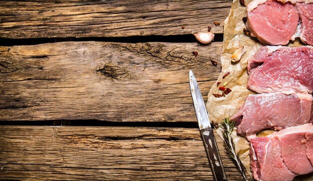 Steaks de viande crue aux épices sur le fond en bois