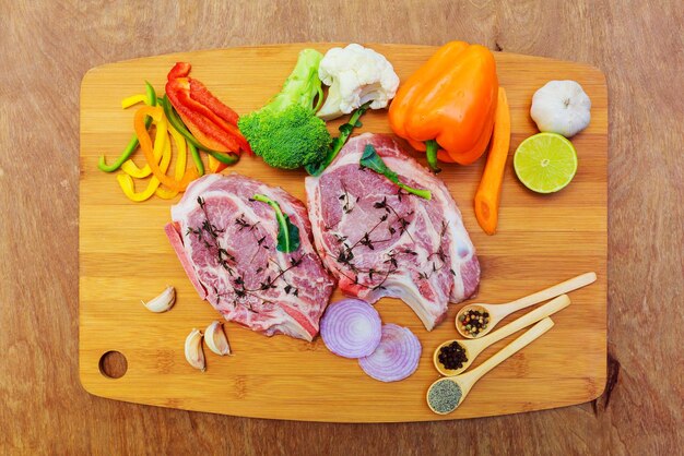 Steaks de viande crue aux épices sur la planche à découper noire.