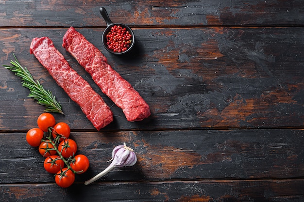 Steaks de viande crue et herbes sur fond de bois