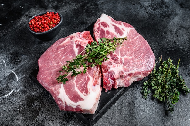 Steaks de viande de porc cru sur une planche de marbre