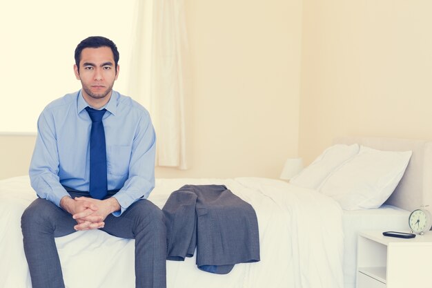 Stern homme à la recherche assis sur son lit