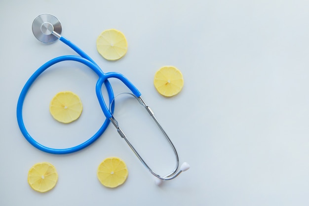 Le stéthoscope bleu se trouve sur un fond blanc entouré de tranches de citron photo de haute qualité