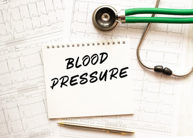 Stéthoscope avec cardiogramme et bloc-notes avec texte PRESSION ARTÉRIELLE. Concept de soins de santé.