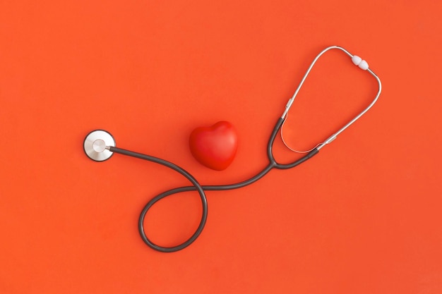 Stéthoscope et coeur sur fond rouge Vue de dessus Mise à plat Concept de médecine