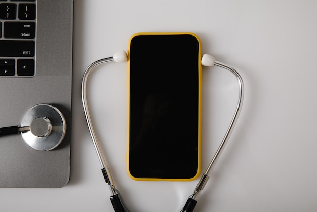 Stéthoscope de concept de consultation de médecin en ligne et smartphone près d'un ordinateur portable