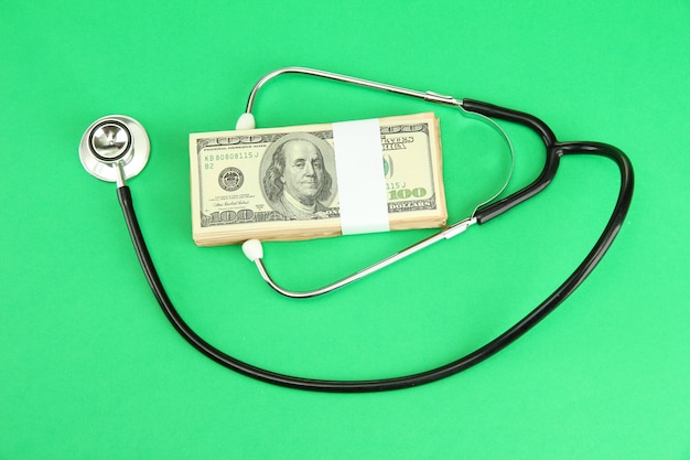 Stéthoscope de concept de coût de soins de santé et dollars sur fond vert