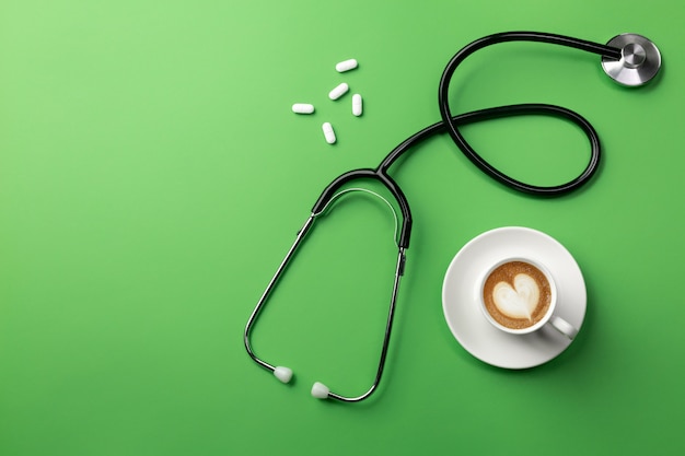 Stéthoscope dans le bureau du médecin avec une tasse de café et des pilules