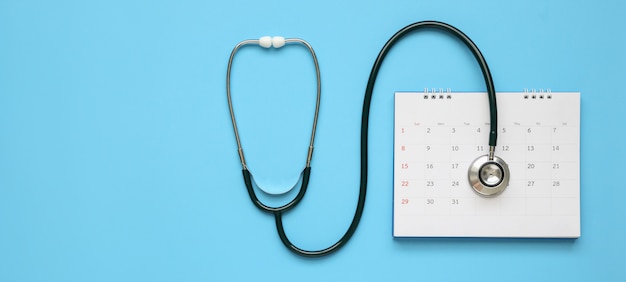 Stéthoscope avec date de page de calendrier sur fond bleu rendez-vous médecin concept médical