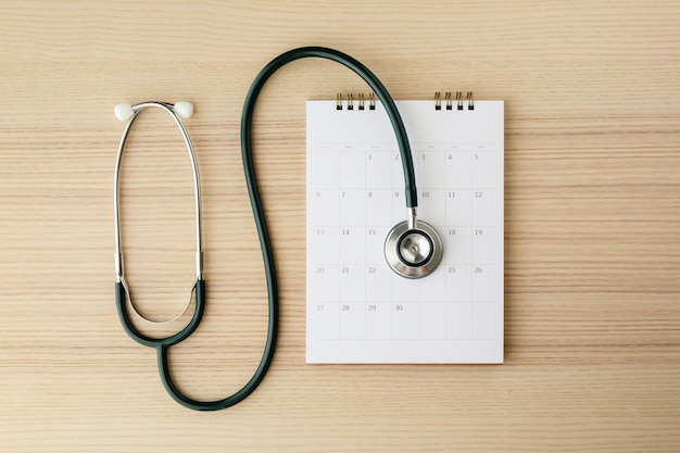 Stéthoscope avec date de page de calendrier sur table en bois