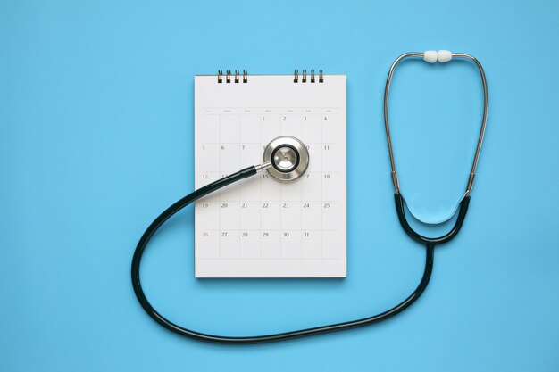 Stéthoscope avec date de page de calendrier sur tableau bleu, concept médical de rendez-vous médecin