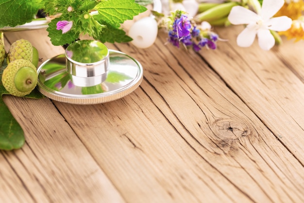 Stéthoscope Avec Diverses Plantes, Feuilles D'herbes Médicinales Et Huiles Saines Sur Table En Bois